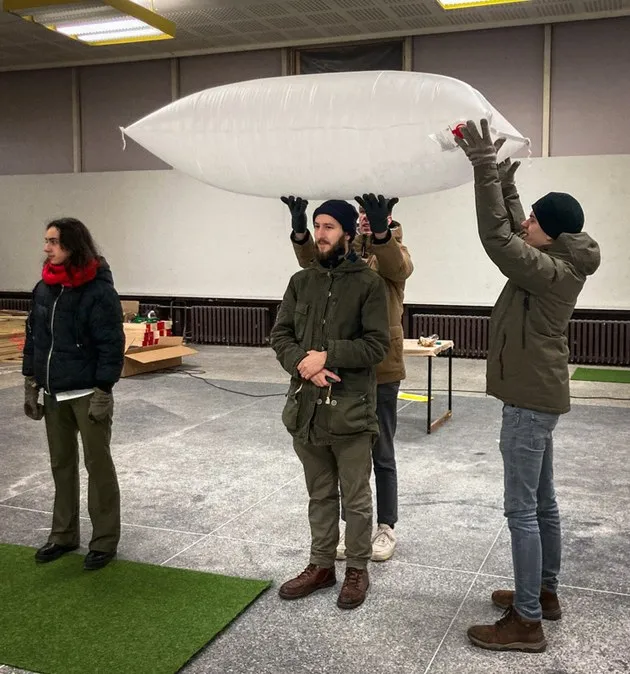 Our team balancing a giant balloon pillow on the head of our 3D designer