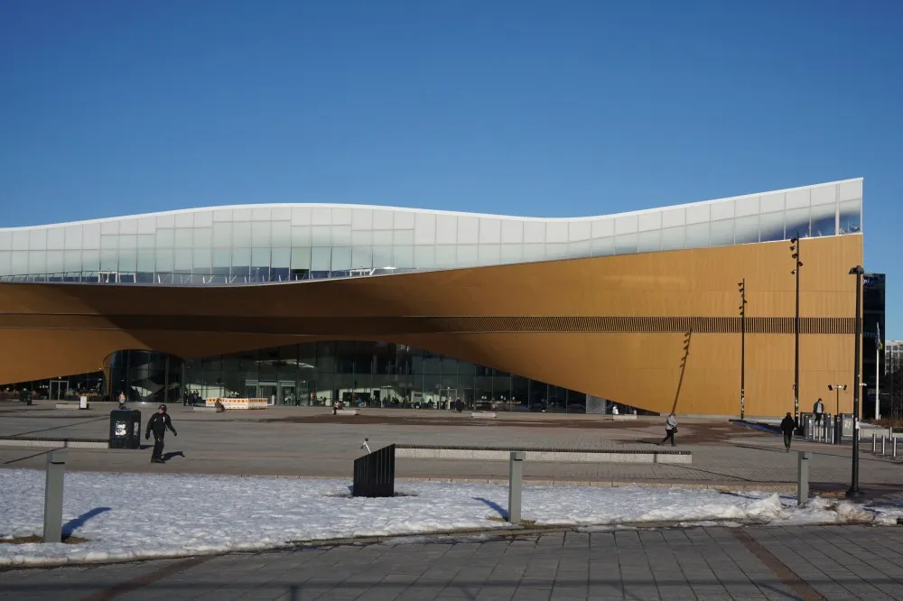Die Bibliothek steht auf einem großen Platz. Sieh selbst besteht aus einer verdrehten Holzfassade und einem Glasaufbau.