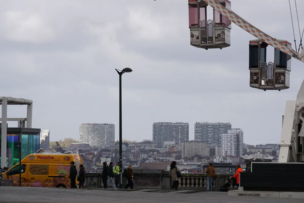 Wagen eines Riesenrades erheben sich über die Stadt. Im Hintergrund stehen große moderne Wohngebäude.