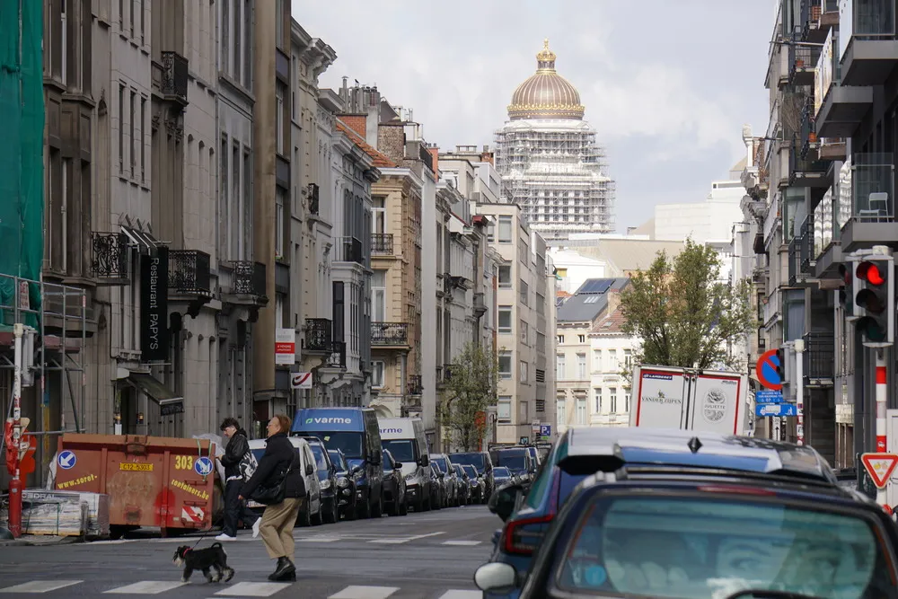Ein eingerüsteter Turm mit rund, gold verzierter Kuppel erhebt sich aus einer Stadt voller Autos und Verkehr.