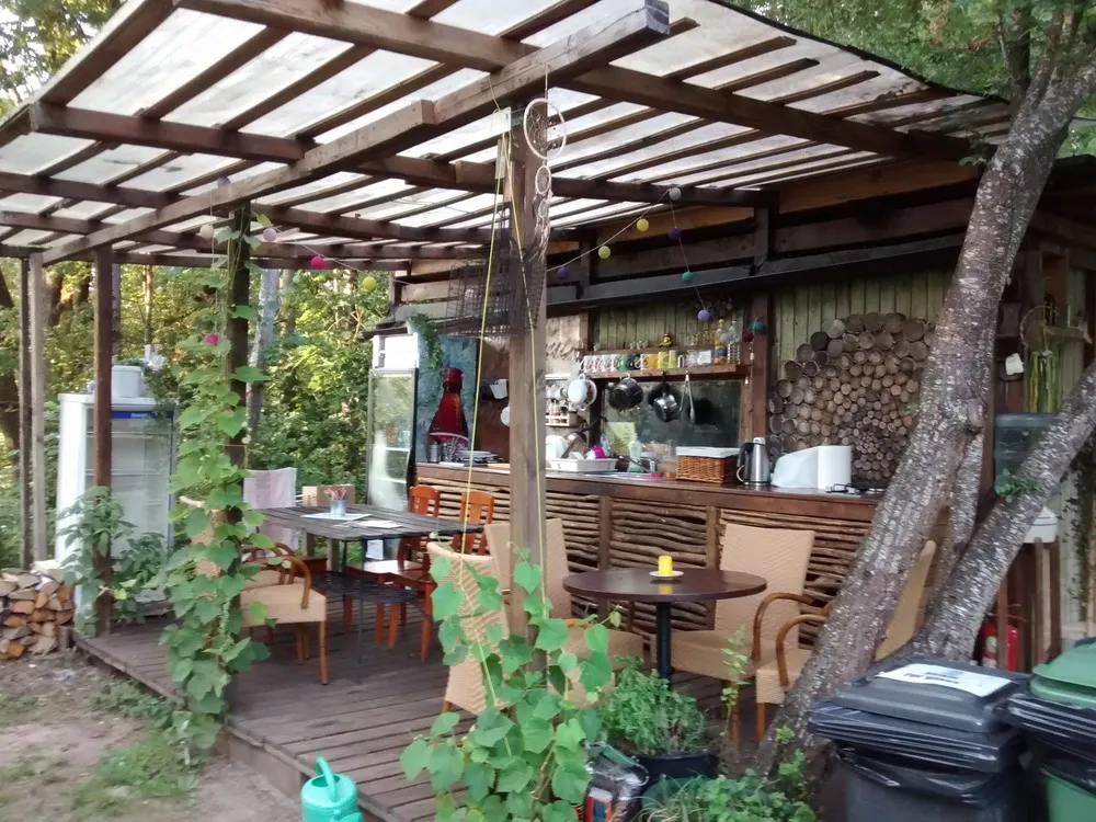 Eine Mischung aus Holzschuppen, Gartenlaube und Küche steht im Wald.