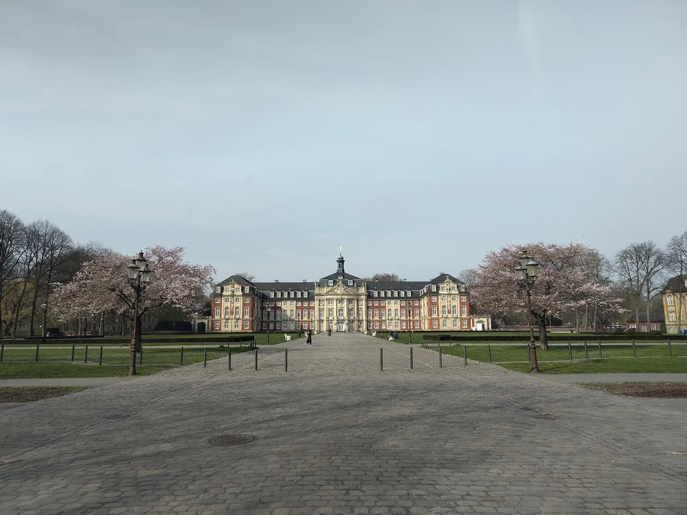 Großes Schloss mit rose blühenden Bäumen links und rechts