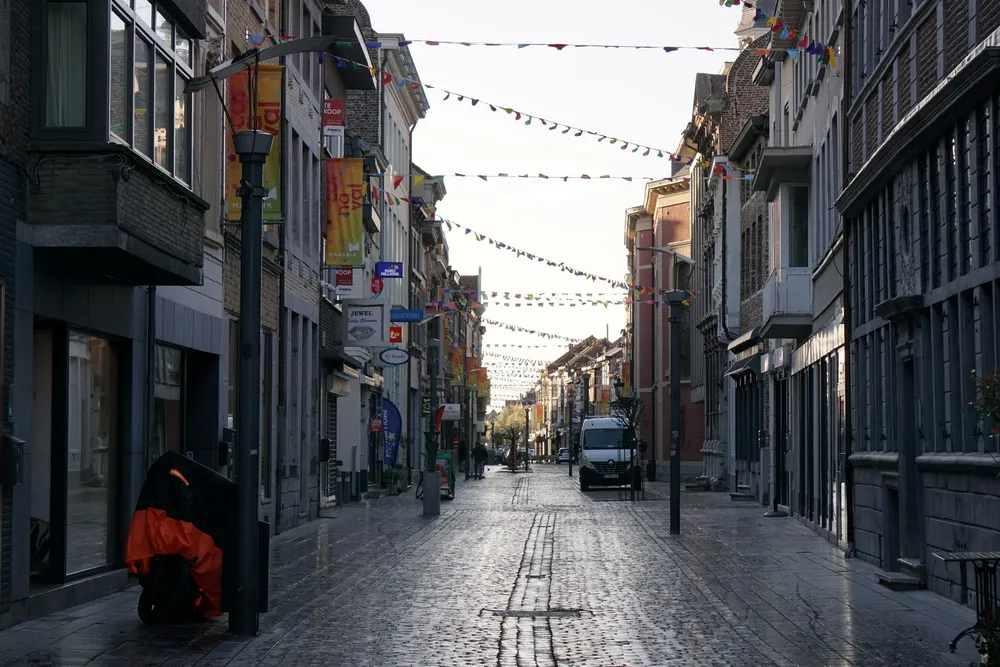 Dämmerung in einer nassen Straße in der Innenstadt von Maaseik. Girlanden zieren die gepflasterte Passage.