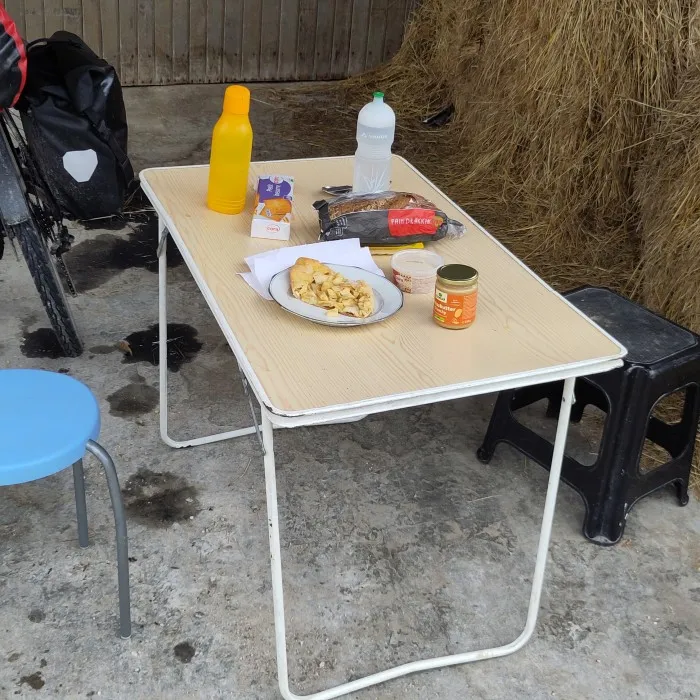 Alter Klapptisch mit zwei Höckern. Darauf ein Apfelkuchen, Brot und Trinkflaschen.