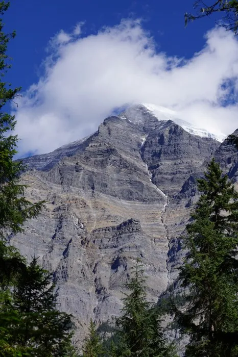 Die schneebedeckte Spitze des Mount Robson streckt sich in eine einzelne Wolke am sonst tiefblauen Himmel.