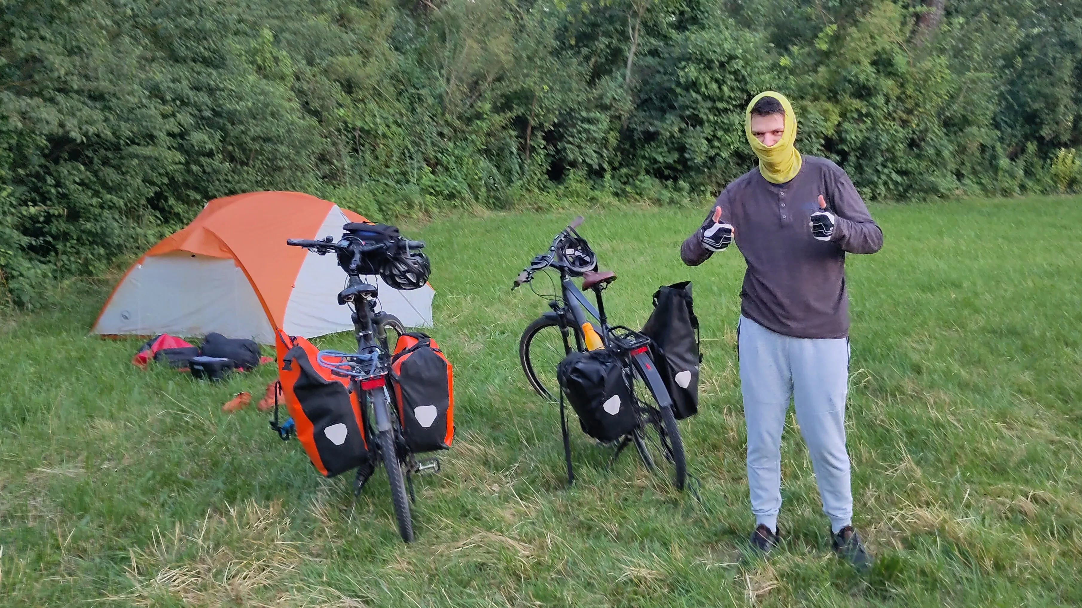 Ich stehe in Vollvermummung vor Zelt und Rädern: Fahrradhandschuhe, lange Jogginghose, Pullover and Schlauchtuch ums Gesicht.