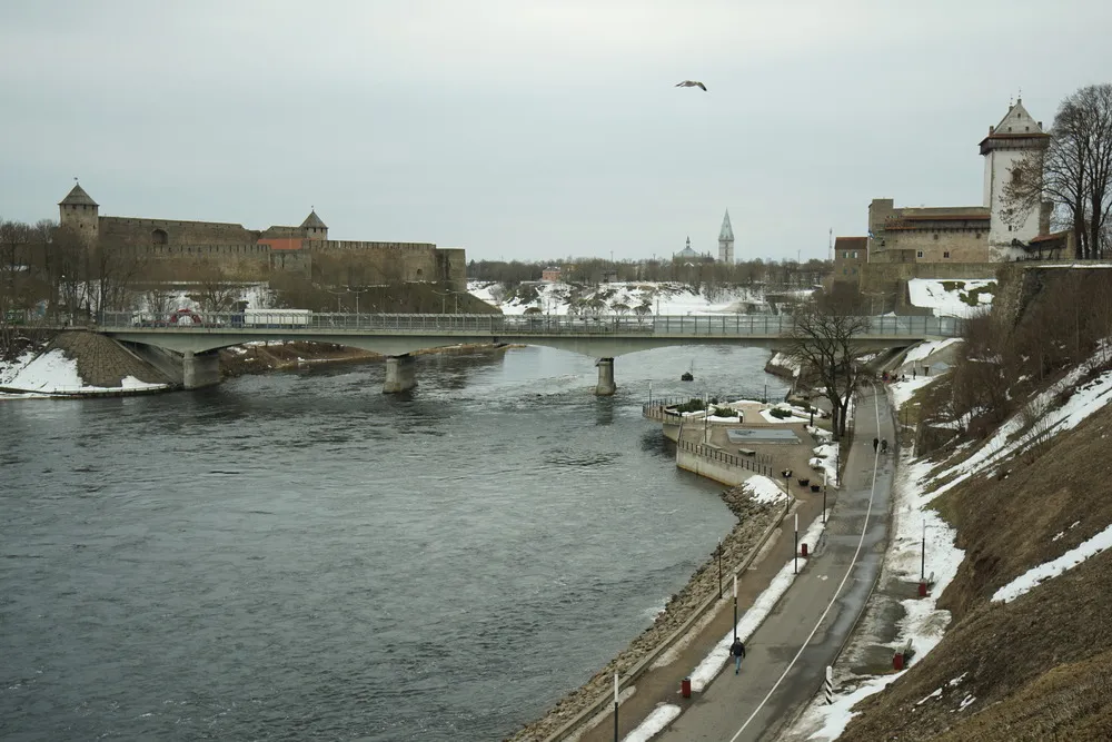 Eine Brücke führt über einen Fluss, links und rechts vom Fluss steht jeweils eine Festung. Links ist Russland, rechts Estland.