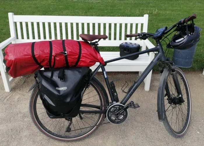 Fahrrad von der Seite. Auf dem Gepäckträger ist ein Packsack, der gute 20 bis 30 cm herausragt.