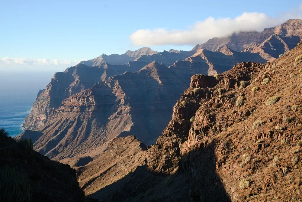 Die Sonne scheint auf die steinigen Berge vor der Küste.