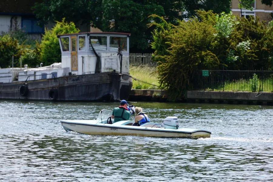 Zwei Personen in einem Kanu auf der Themse. Einer brüllt durch ein Megaphon auf Ruderer in einem anderen Boot außerhalb des Bildes ein.